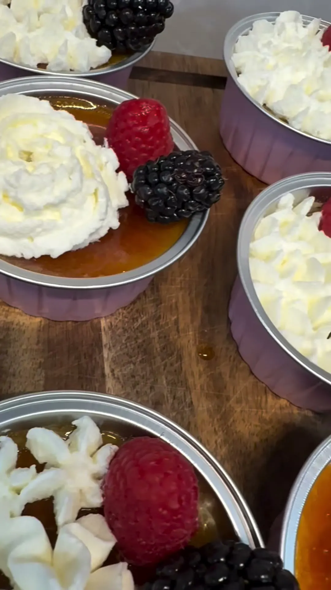 Crème caramel cups topped with cream and berries