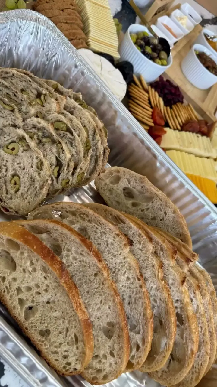 A tray of sliced specialty sourdough next to a cheese board