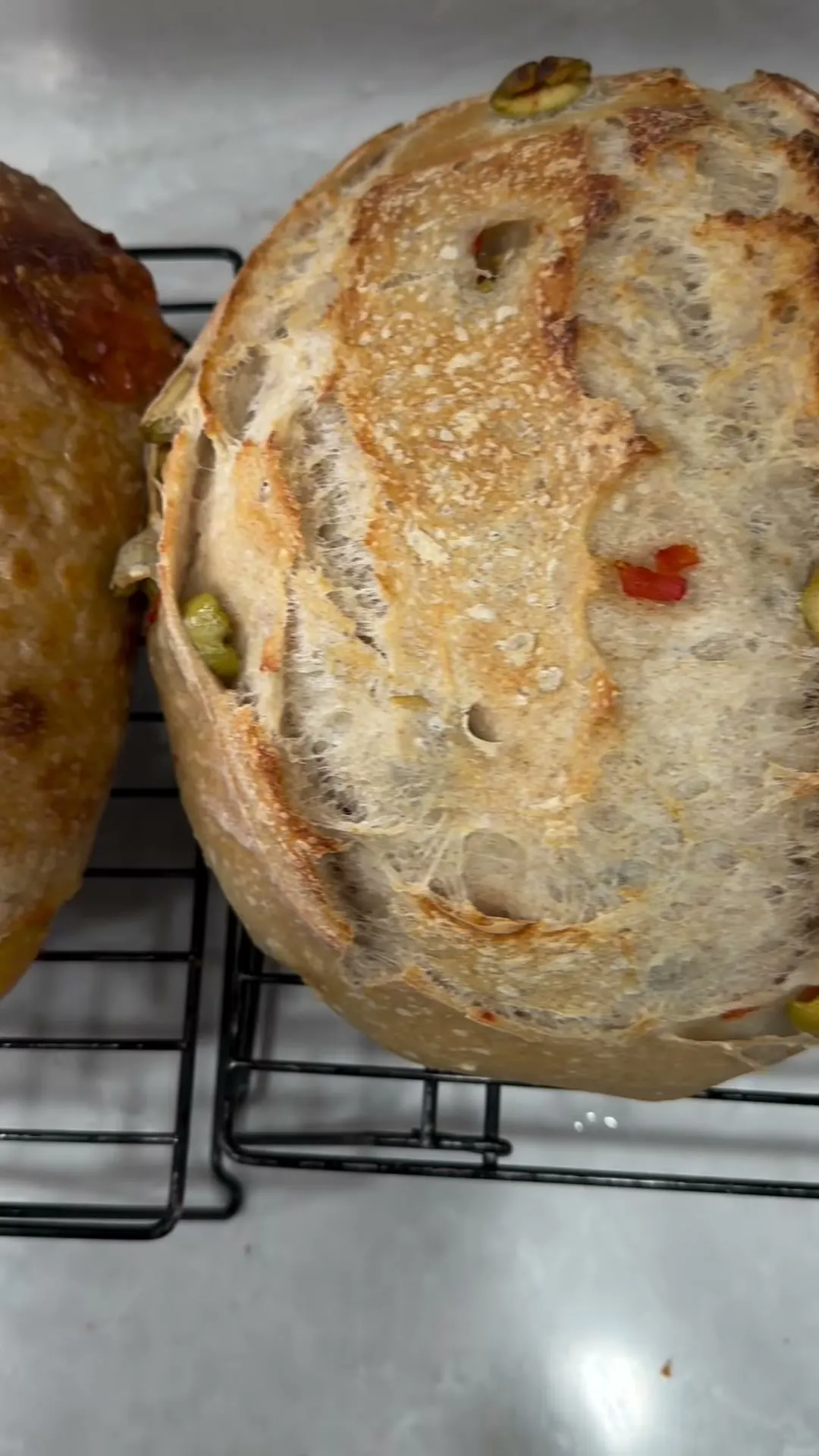 A rustic sourdough boule cooling on a wire rack